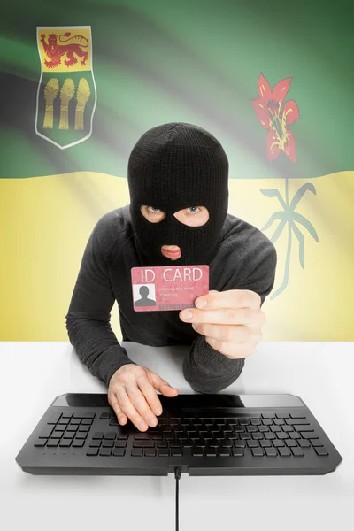 Hacker with Canadian province flag on background holding ID card in hand - Saskatchewan — Stock Photo, Image