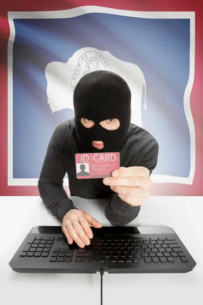 Hacker with USA states flag on background and ID card in hand - Wyoming —  Fotos de Stock