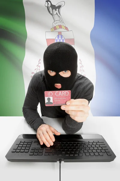 Hacker with Canadian province flag on background holding ID card in hand - Yukon —  Fotos de Stock