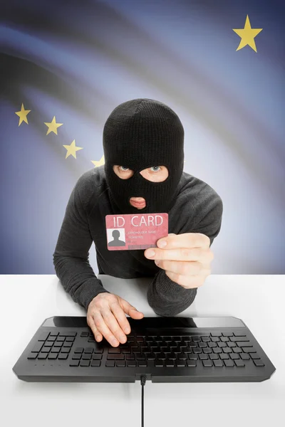 Hacker with USA states flag on background holding ID card in hand - Alaska — Stok fotoğraf