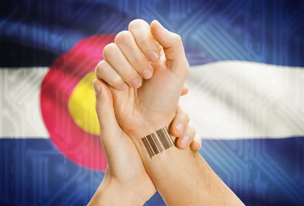 Barcode ID number on wrist and USA states flags on background - Colorado — Foto de Stock
