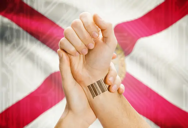 Barcode ID number on wrist and USA states flags on background - Florida — 图库照片