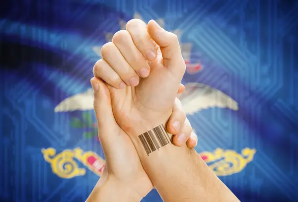 Barcode ID number on wrist and USA states flags on background - North Dakota — Stock Photo, Image