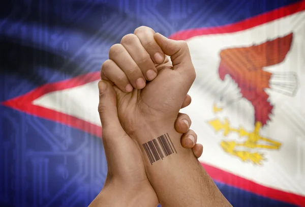 Barcode ID number on wrist of dark skinned person and national flag on background - American Samoa — Stok fotoğraf