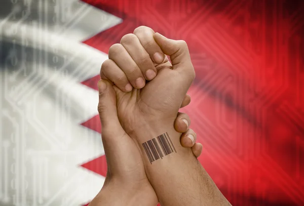 Barcode ID number on wrist of dark skinned person and national flag on background - Bahrain — Stock fotografie
