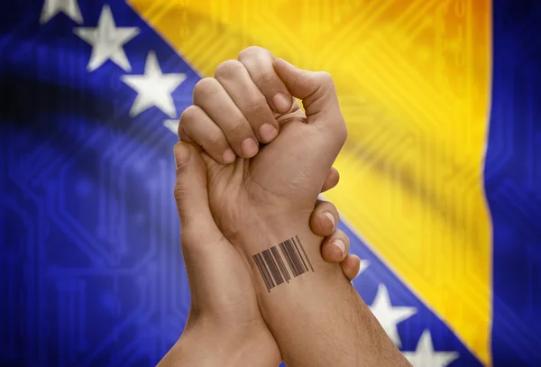 Barcode ID number on wrist of dark skinned person and national flag on background - Bosnia and Herzegovina — Foto Stock