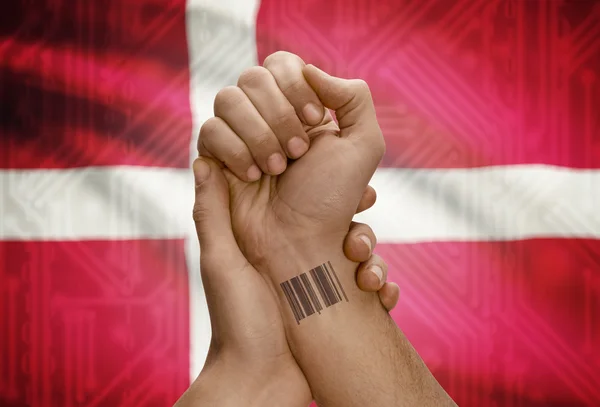 Barcode ID number on wrist of dark skinned person and national flag on background - Denmark — Foto Stock