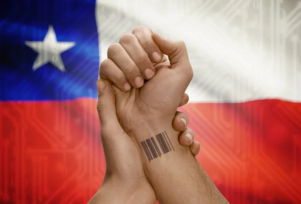 Barcode ID number on wrist of dark skinned person and national flag on background - Chile — Stock Photo, Image