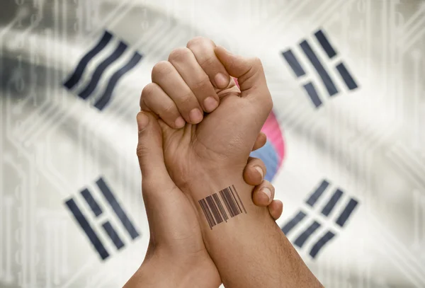 Barcode ID number on wrist of dark skinned person and national flag on background - South Korea — Stock Photo, Image
