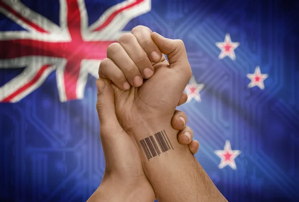 Barcode ID number on wrist of dark skinned person and national flag on background - New Zealand — Foto de Stock