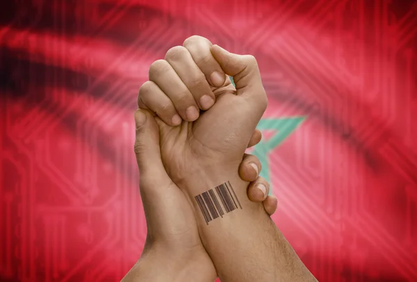 Barcode ID number on wrist of dark skinned person and national flag on background - Morocco — Stock Photo, Image