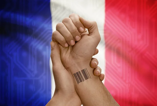 Barcode ID number on wrist of dark skinned person and national flag on background - France —  Fotos de Stock