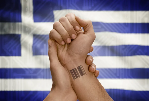 Barcode ID number on wrist of dark skinned person and national flag on background - Greece — Stock Photo, Image