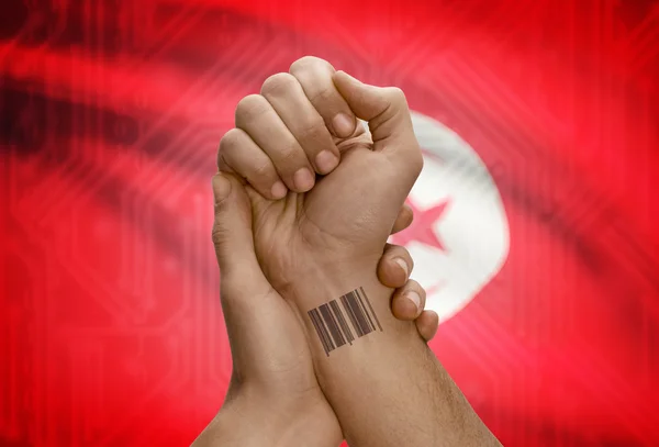 Barcode ID number on wrist of dark skinned person and national flag on background - Tunisia — Foto Stock