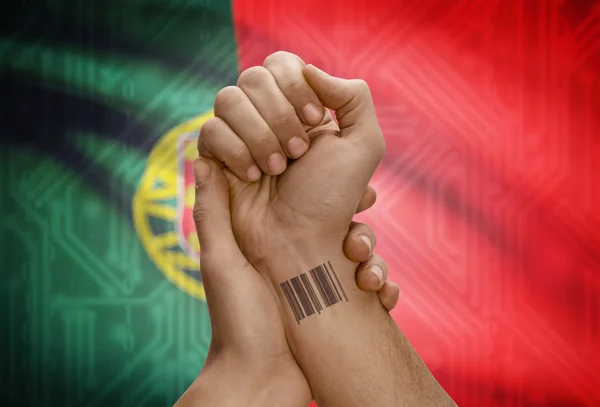 Barcode ID number on wrist of dark skinned person and national flag on background - Portugal — Stockfoto