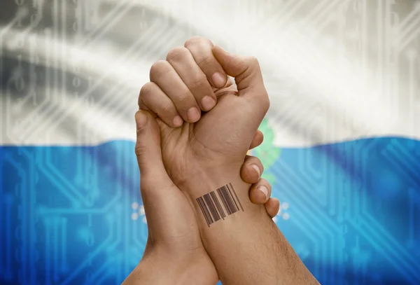 Barcode ID number on wrist of dark skinned person and national flag on background - San Marino — 图库照片