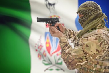 Male in muslim keffiyeh with gun in hand and Canadian province flag on background - Yukon