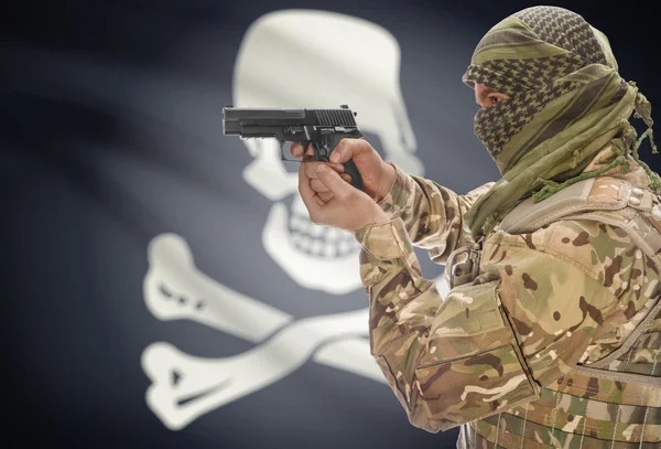 Male in muslim keffiyeh with gun in hand and flag on background - Jolly Roger - symbol of piracy — Stok Foto