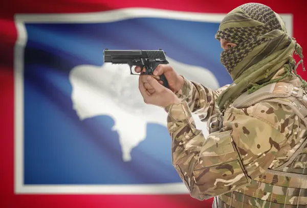 Male in muslim keffiyeh with gun in hand and flag on background - Wyoming — Stockfoto