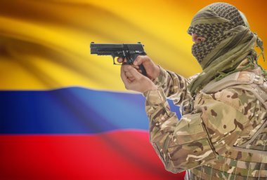 Male in muslim keffiyeh with gun in hand and national flag on background - Colombia