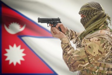 Male in muslim keffiyeh with gun in hand and national flag on background - Nepal