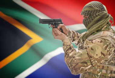 Male in muslim keffiyeh with gun in hand and national flag on background - South Africa