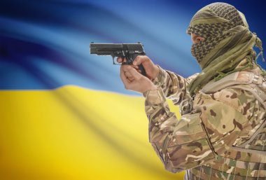 Male in muslim keffiyeh with gun in hand and national flag on background - Ukraine