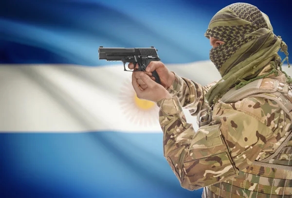 Male in muslim keffiyeh with gun in hand and national flag on background - Argentina — Stok fotoğraf