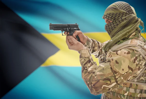 Male in muslim keffiyeh with gun in hand and national flag on background - Bahamas — 图库照片