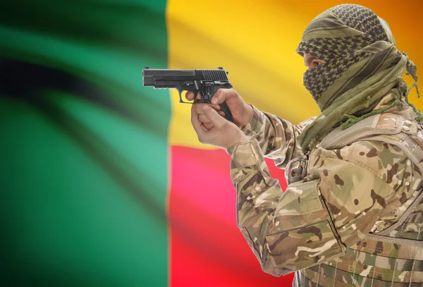 Male in muslim keffiyeh with gun in hand and national flag on background - Benin — стокове фото