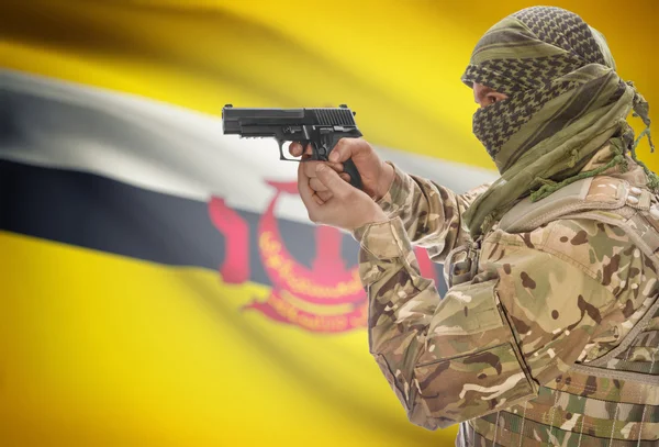 Male in muslim keffiyeh with gun in hand and national flag on background - Brunei — 图库照片