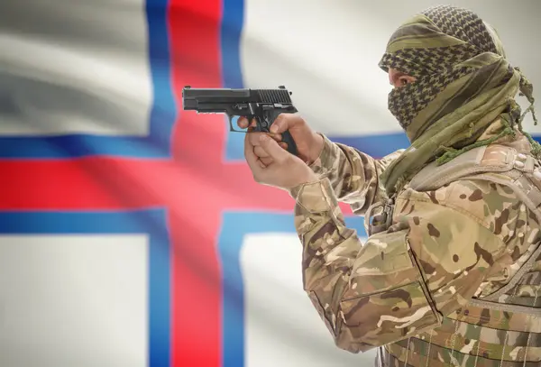 Male in muslim keffiyeh with gun in hand and national flag on background - Faroe Islands — Stock Photo, Image