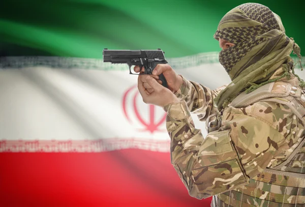 Male in muslim keffiyeh with gun in hand and national flag on background - Iran — Stockfoto