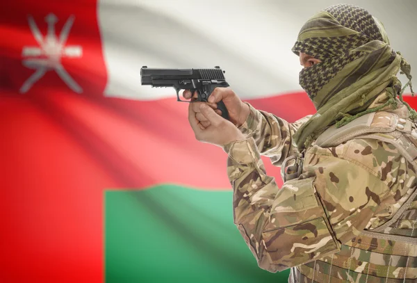 Male in muslim keffiyeh with gun in hand and national flag on background - Oman — стокове фото