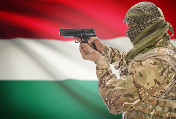 Male in muslim keffiyeh with gun in hand and national flag on background - Hungary — Stok fotoğraf