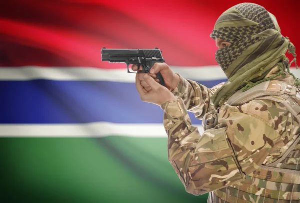 Male in muslim keffiyeh with gun in hand and national flag on background - Gambia — стокове фото