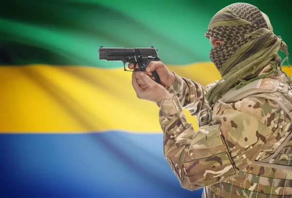 Male in muslim keffiyeh with gun in hand and national flag on background - Gabon — Stok fotoğraf