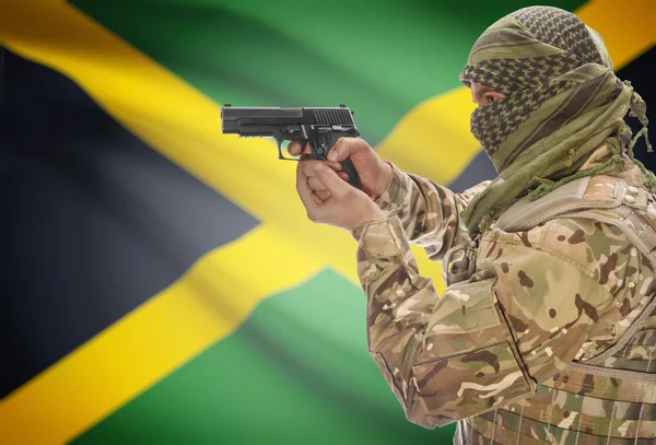 Male in muslim keffiyeh with gun in hand and national flag on background - Jamaica — Stock Photo, Image