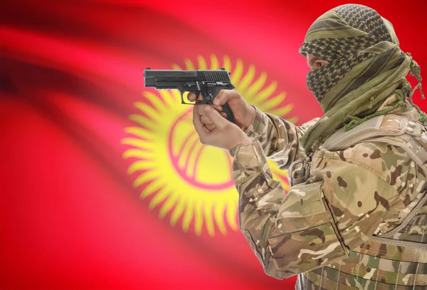 Male in muslim keffiyeh with gun in hand and national flag on background - Kyrgyzstan — Stok fotoğraf