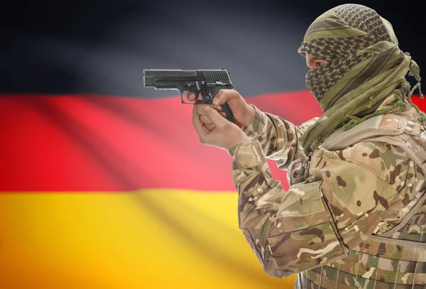 Male in muslim keffiyeh with gun in hand and national flag on background - Germany — Stock Photo, Image
