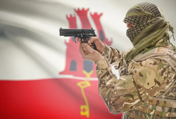 Male in muslim keffiyeh with gun in hand and national flag on background - Gibraltar — Stock Photo, Image