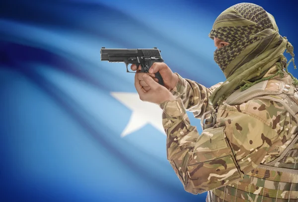 Male in muslim keffiyeh with gun in hand and national flag on background - Somalia — Stock Photo, Image