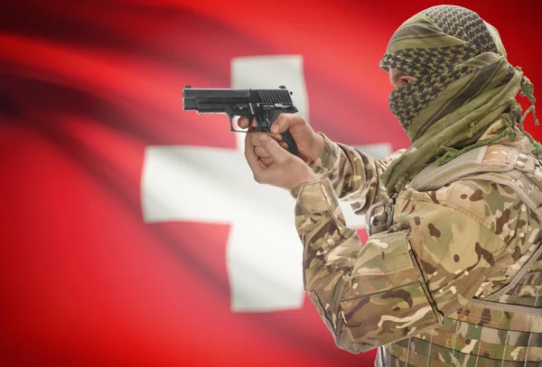 Male in muslim keffiyeh with gun in hand and national flag on background - Switzerland — Stock Photo, Image