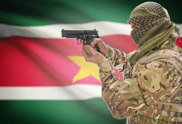 Male in muslim keffiyeh with gun in hand and national flag on background - Suriname — Stok Foto