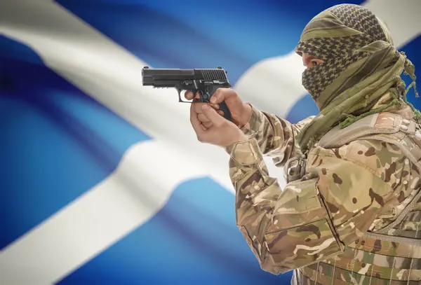 Male in muslim keffiyeh with gun in hand and national flag on background - Scotland — Stock Fotó