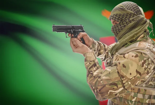 Male in muslim keffiyeh with gun in hand and national flag on background - Zambia — Stok Foto