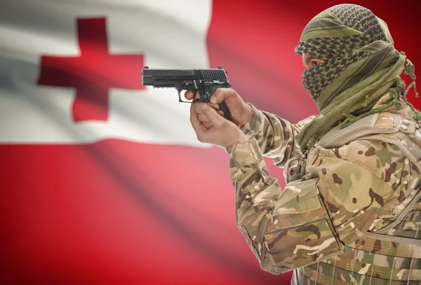 Male in muslim keffiyeh with gun in hand and national flag on background - Tonga — Stock Photo, Image