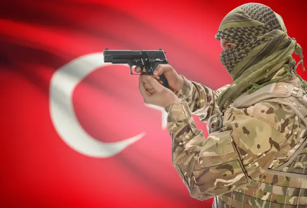 Male in muslim keffiyeh with gun in hand and national flag on background - Turkey — Foto Stock