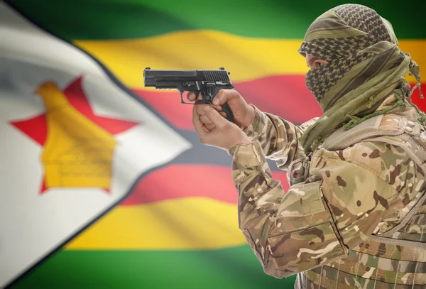 Male in muslim keffiyeh with gun in hand and national flag on background - Zimbabwe — Fotografia de Stock