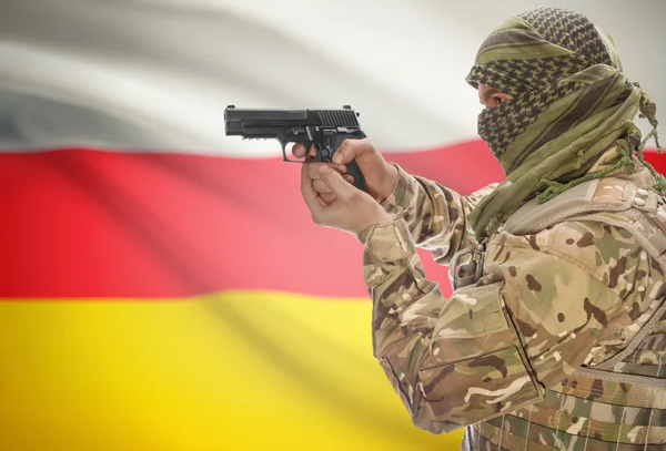 Male in muslim keffiyeh with gun in hand and national flag on background - South Ossetia — Stok fotoğraf